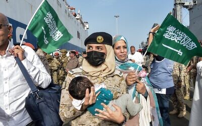 إحدى عناصر البحرية السعودية تحمل طفلاً أثناء وصول الفارين من القتال إلى قاعدة الملك فيصل البحرية في جدة، 26 أبريل 2023 (Amer HILABI / AFP)