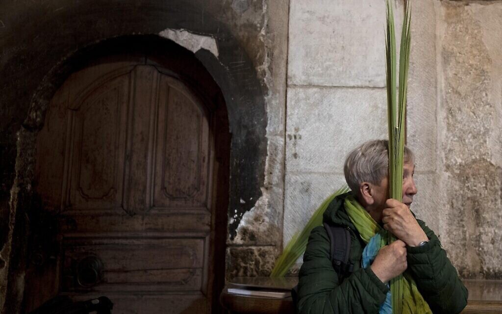 امرأة تحمل سعف النخيل خلال قداس أحد الشعانين في كنيسة القيامة، حيث يعتقد العديد من المسيحيين أن المسيح قد صلب ودفن وقام من الموت، في البلدة القديمة في القدس، 2 أبريل، 2023. (AP Photo / Maya Alleruzzo) )