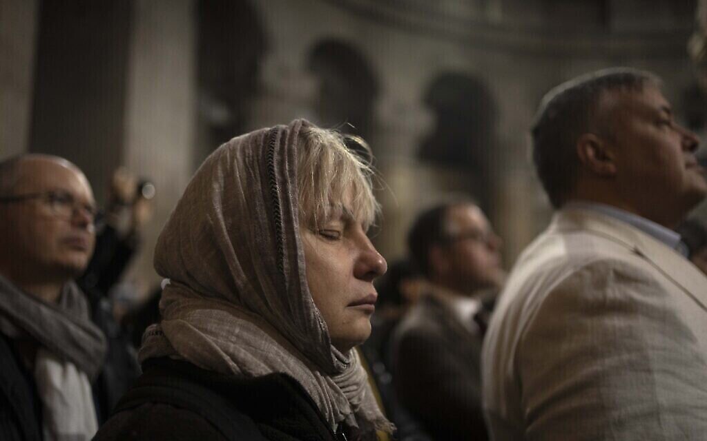 امرأة تشارك في قداس أحد الشعانين في كنيسة القيامة، حيث يعتقد المسيحيون أن يسوع قد صلب ودفن وقام من الموت، في البلدة القديمة في القدس، 2 أبريل، 2023. (AP Photo / Maya Alleruzzo)