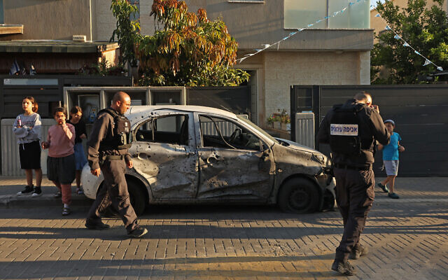 قوات الأمن تتفقد سيارة مدمرة في مدينة سديروت بجنوب البلاد بعد إطلاق صواريخ من غزة، 2 مايو، 2023. (Gil Cohen-Magen / AFP)