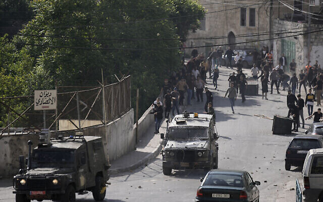 توضيحية: فلسطينيون يطاردون مركبات عسكرية اسرائيلية تغادر نابلس، 9 مايو، 2023. (AP / Majdi Mohammed)
