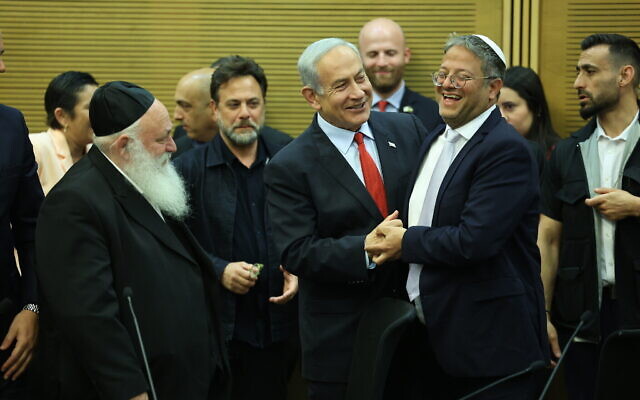 رئيس الوزراء بنيامين نتنياهو (وسط الصورة) يصافح وزير الأمن القومي إيتمار بن غفير (يمين) في الكنيست، إلى جانب رؤساء أحزاب أخرى شريكة في الإئتلاف قبل التصويت على تمرير ميزانية الدولة 2023-2024، 23 مايو، 2023. (Yonatan Sindel / Flash90)