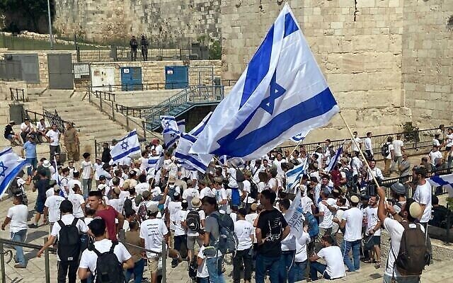 شبان إسرائيليون يرقصون مع الأعلام الإسرائيلية عند باب العامود في البلدة القديمة في القدس في 29 مايوـ 2022، خلال مسيرة لليمنين المتطرف للاحتفال بـ"يوم القدس". (Aaron Boxerman/Times of Israel)