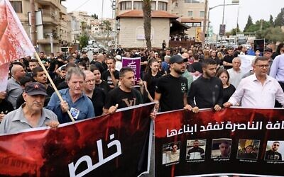 متظاهرون يحملون لافتة عليها صور لخمسة عرب اسرائيليين قُتلوا في إطلاق نار في اليوم السابق، خلال مظاهرة احتجاجا على مقتل الخمسة في يافة الناصرة ، غرب الناصرة، 9 يونيو، 2023. (Ahmad Gharabli / AFP)