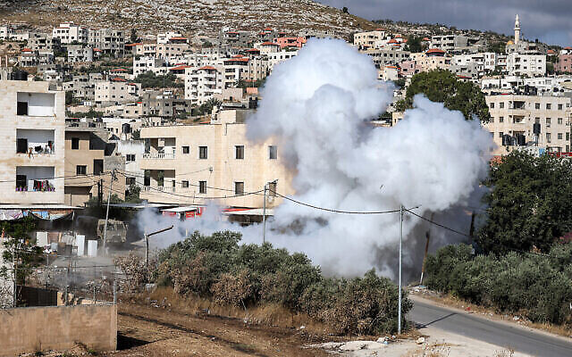 دخان يتصاعد من انفجار عبوة ناسفة خلفها مسلحون فلسطينيون على طريق خلال عملية للجيش الإسرائيلي في جنين بالضفة الغربية، 19 يونيو، 2023. (Photo by Jaafar ASHTIYEH / AFP)