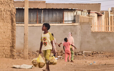 طفل يحمل أكياس الخبز وهو يسير في أحد شوارع الخرطوم في 20 يونيو 2023 - أتاح وقف إطلاق النار لمدة ثلاثة أيام والذي سينتهي في 21 يونيو فجرا فترة راحة قصيرة للعاصمة الخرطوم التي عصفت بها الحرب التي اندلعت في 15 أبريل بين جنرالين متنافسين.  (AFP)