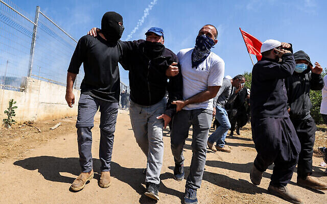 أبناء الطائفة الدرزية يحملون متظاهرا أصيب خلال احتجاجات ومواجهات في قرية مجدل شمس في هضبة الجولان، 21 يونيو، 2023.  (Jalaa MAREY / AFP)