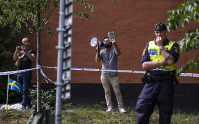 سلوان موميكا يحمل القرآن أثناء احتجاجه خارج مسجد في ستوكهولم، 28 يونيو، 2023، خلال عيد الأضحى.(Jonathan NACKSTRAND / AFP)