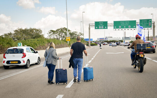 مسافرون في طريقهم إلى مطار بن غوريون، حيث تأخرت الرحلات الجوية بسبب قطع المتظاهرين الطريق إلى المطار، 9 مارس 2023 (Avshalom Sassoni / Flash90)
