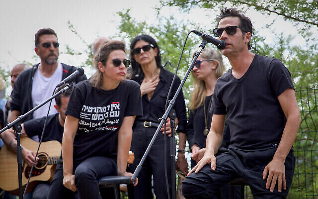 شيرا جيفين (وسط الصورة من اليسار)، في جنازة والدها المؤلف والموسيقي يهوناتان غيفن في مقبرة نهلال، شمال إسرائيل، 21 أبريل 2023. ترتردي شيرا غيفن قيمصا كُتب عليه "لا ديمقراطية مع الاحتلال".