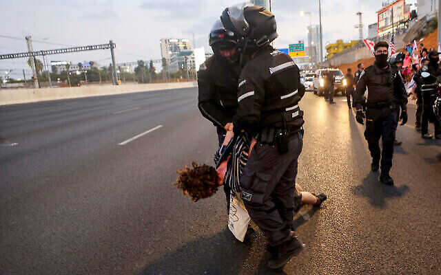 الشرطة تحتجز رجلا أثناء قيام المتظاهرين بإغلاق طريق أيالون السريع خلال مظاهرة في تل أبيب احتجاجا على خطة الحكومة لإصلاح النظام القضائي، 1 يوليو، 2023. ( GIL COHEN-MAGEN / AFP)