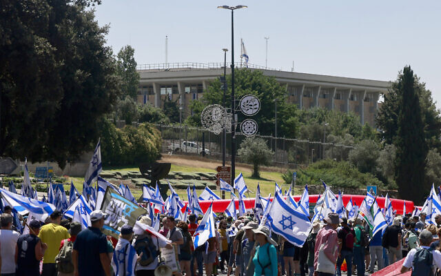 متظاهرون يرفعون الأعلام الوطنية أثناء تجمعهم أمام الكنيست في القدس، 11 يوليو 2023 (Menahem KAHANA / AFP)