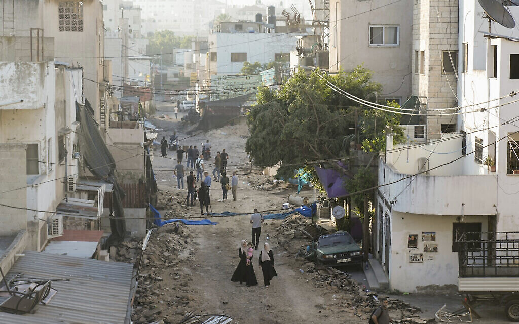 فلسطينيون يسيرون على طريق مدمر في مخيم جنين بالضفة الغربية ، 5 يوليو 2023، بعد أن سحب الجيش الإسرائيلي قواته من المخيم.  (AP Photo/Majdi Mohammed)