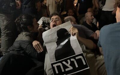 متظاهر في القدس يحمل لافتة كتب عليها بالعبرية "قاتل"، تصور الشرطي الذي تمت تبرئته الذي قتل إياد الحلاق بعد أن أطلق النار عليه في عام 2020. (Charlie Summers / Times of Israel)