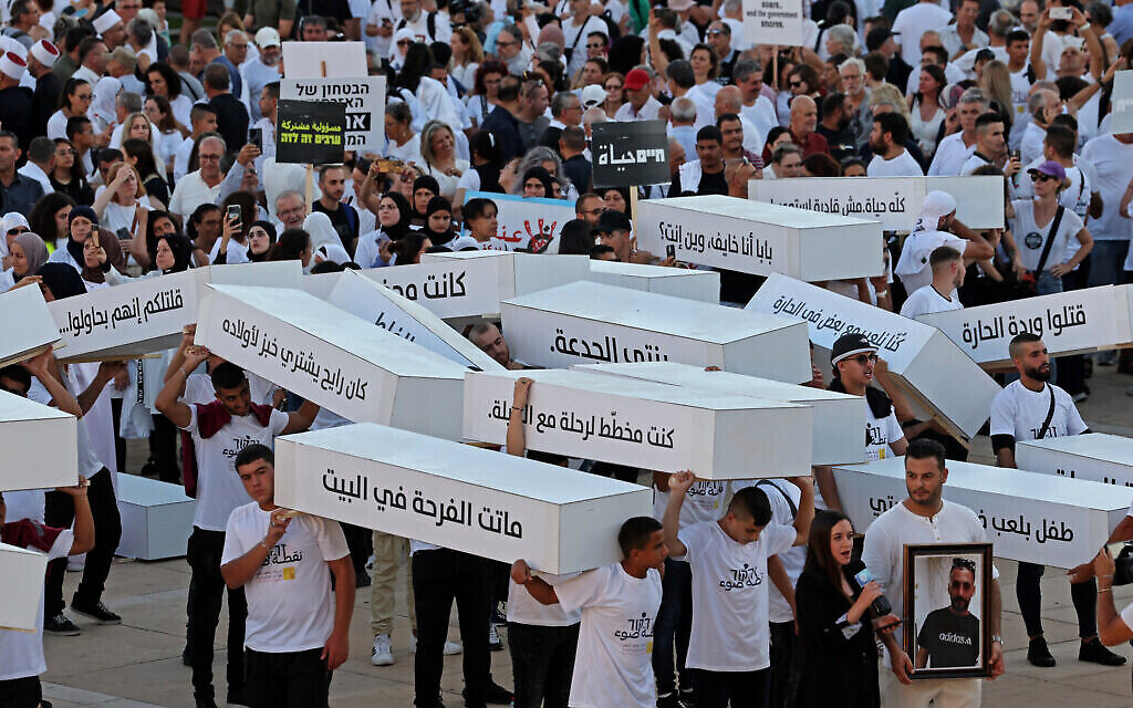 نشطاء يسيرون حاملين توابيت رمزية تندد بجرائم العنف في المجتمع العربية في 6 أغسطس، 2023، في تل أبيب. (Jack Guez/AFP)
