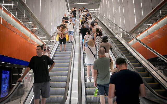 أشخاص يستخدمون الدرج الكهربائي في محطة قطار خفيف في تل أبيب في اليوم الأول من الخدمة، 18 أغسطس، 2023. (Miriam Alster / Flash90)