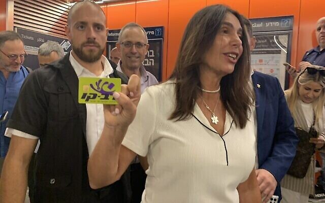وزيرة المواصلات ميري ريغيف تحمل بطاقة راف- كاف التي أعطاها لها أحد الصحفيين قبل دخول محطة اللنبي. (Charlie Summers/Times of Israel)