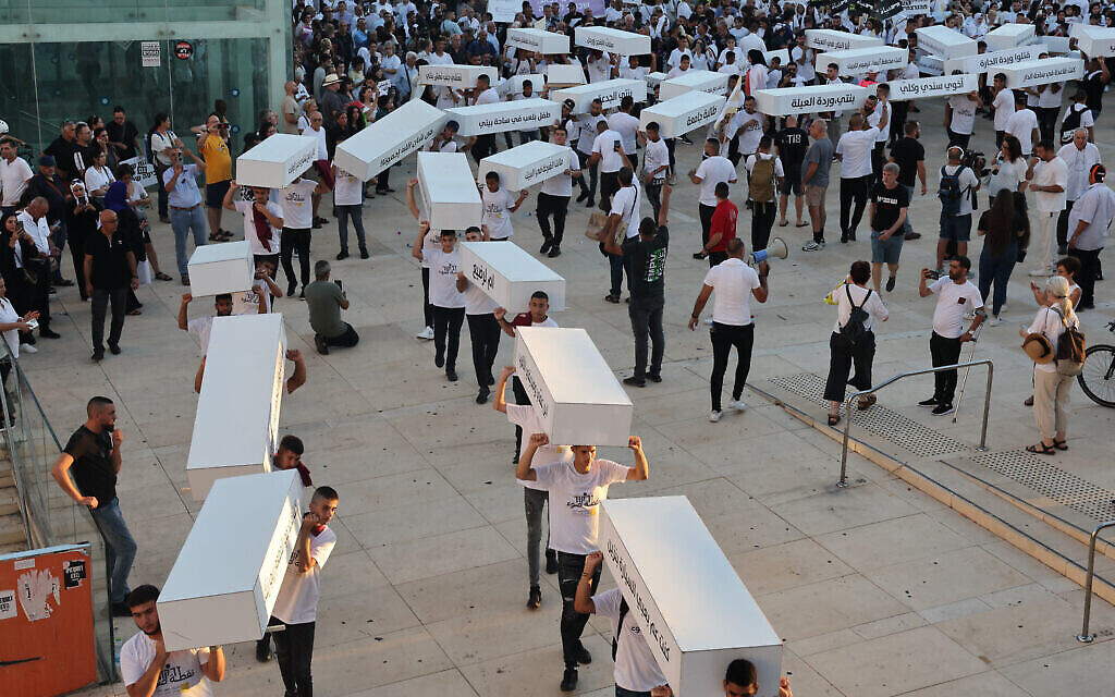 نشطاء يسيرون حاملين توابيت رمزية تندد بجرائم العنف في المجتمع العربية في 6 أغسطس، 2023، في تل أبيب. (Jack Guez/AFP)