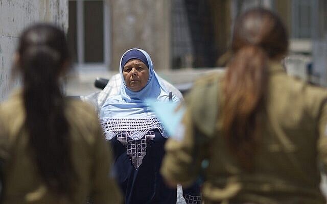 امرأة عربية إسرائيلية تمر من أمام مجندات إسرائيليات. (AP/Ariel Schalit/File)