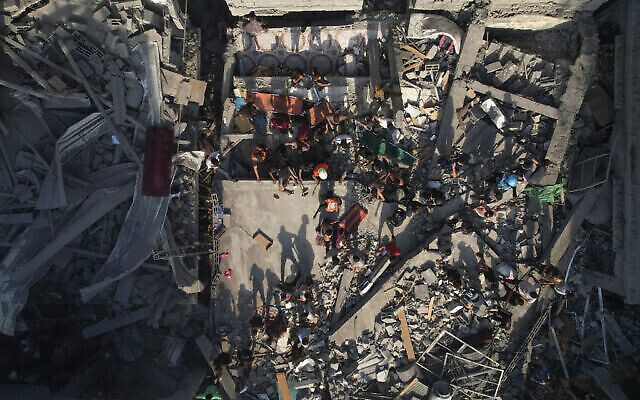 فلسطينيون يتفقدون أنقاض المباني التي ضربتها غارة جوية إسرائيلية في مخيم الشاطئ في غزة يوم الخميس، 12 أكتوبر، 2023. (AP/Hatem Moussa)