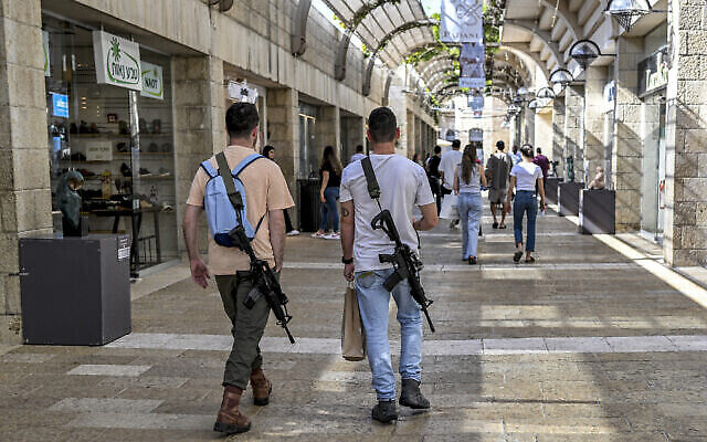 توضيحية: رجلان إسرائيليان، مسلحان ببندقيتين هجوميتين أوتوماتيكيتين أمريكيتي الصنع من طراز M16، يسيران في مركز ماميلا للتسوق في القدس، 25 أكتوبر، 2023. (Yuri Cortez/AFP)