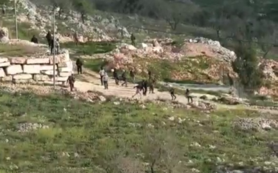 مستوطنون ملثمون يلقون الحجارة على منازل فلسطينية في قرية بورين شمال الضفة الغربية، 3 مارس، 2023. (Yesh Din)