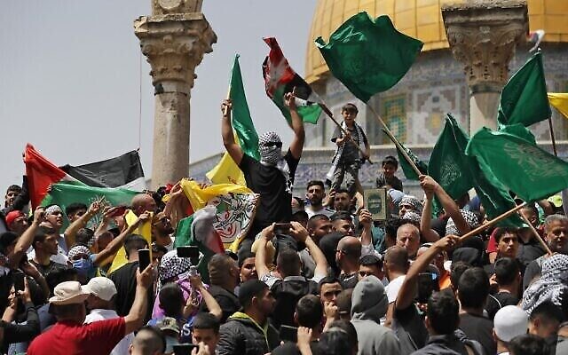 فلسطينيون يلوحون بالأعلام الفلسطينية والإسلامية أثناء تجمعهم في المسجد الأقصى في الحرم القدسي، بعد صلاة الجمعة الأخيرة من شهر رمضان المبارك، في 29 أبريل، 2022. (Ahmad Gharabli/AFP)