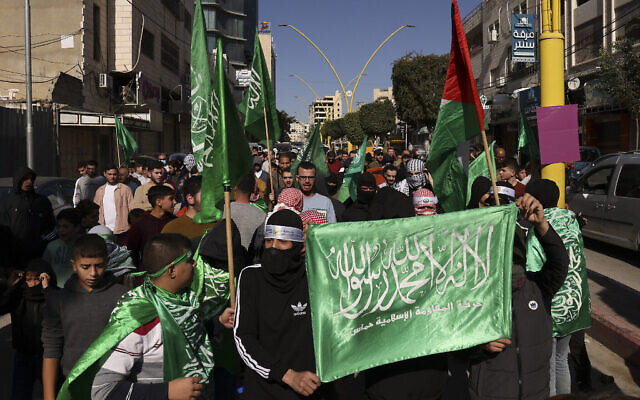 أرشيف: فلسطينيون يرفعون علم حركة حماس خلال مظاهرة في مدينة الخليل بالضفة الغربية، في 1 ديسمبر، 2023. (Hazem Bader/AFP)