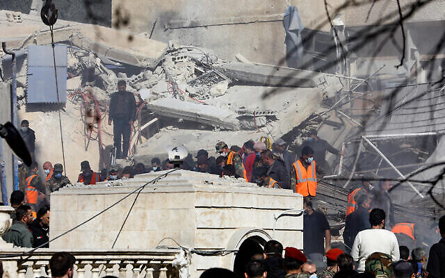 أشخاص وعمال إنقاذ يتجمعون أمام مبنى دُمر في غارة إسرائيلية مزعومة في دمشق، 20 يناير، 2024. (Louai Beshara / AFP)