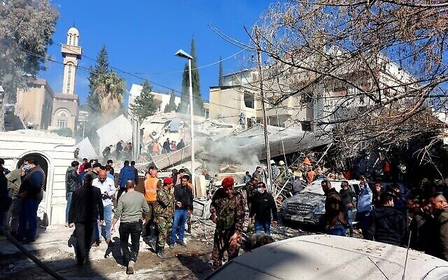 أشخاص وقوات أمنية يتجمعون أمام مبنى دمر في غارة إسرائيلية في دمشق في 20 يناير، 2024. (AFP)