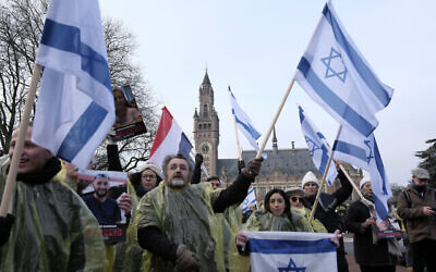 متظاهرون يلوحون بالأعلام الإسرائيلية ويحملون صور الرهائن الذين تم اختطافهم خلال هجوم حماس الدامي في 7 أكتوبر على إسرائيل، خلال مظاهرة خارج محكمة العدل الدولية في لاهاي، هولندا، 11 يناير، 2024. (AP Photo / Patrick Post)