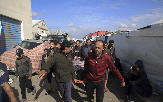 فلسطينيون يحملون جثة شخص قُتل في قصف على مركز للتدريب المهني تابع للأونروا، والذي يستخدمه النازحون كمأوى في خان يونس، جنوب قطاع غزة، الأربعاء، 24 يناير، 2024. (AP Photo/Ramez Habboub)
