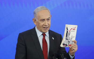 رئيس الوزراء بنيامين نتنياهو يحمل نسخة عربية من كتاب “كفاحي” لأدولف هتلر الذي تم العثور عليه في غزة خلال مؤتمر صحفي في وزارة الدفاع في تل أبيب، 18 يناير، 2024. (Tomer Appelbaum/POOL)