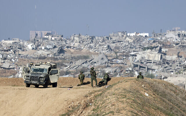 تظهر هذه الصورة الملتقطة من الحدود الإسرائيلية مع شمال قطاع غزة جنودا إسرائيليين يراقبون مدينة غزة من موقع في 1 يناير، 2024. (Menahem KAHANA / AFP)