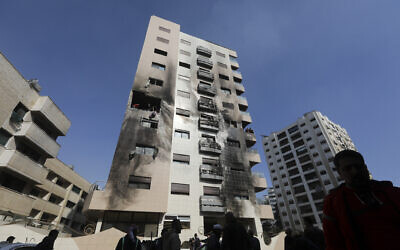 أشخاص يتفقدون مبنى تعرض لقصف جوي نسب لإسرائيلي في منطقة كفرسوسة في العاصمة السورية دمشق، 21 فبراير، 2024. (Louai Beshara/AFP)