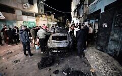 أشخاص يتفقدون سيارة محترقة في غارة إسرائيلية في مدينة جنين بالضفة الغربية خلال الليل، 22 فبراير، 2024. (Mohammad Mansur/AFP)