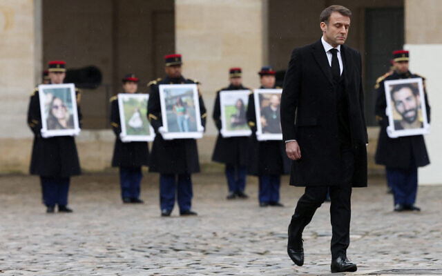 الرئيس الفرنسي إيمانويل ماكرون يمر أمام الحرس الجمهوري الفرنسي الذي يحمل صور الضحايا الفرنسيين لهجوم حماس في 7 أكتوبر 2023 في إسرائيل، خلال حفل أقيم في نصب إنفاليد التذكاري، 7 فبراير، 2024. (Gonzalo Fuentes/Pool via AP)