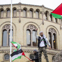 رجل يلوح بالعلم الفلسطيني أمام مبنى البرلمان النرويجي خلال مظاهرة في أوسلو، 28 أكتوبر، 2023. (Frederik Ringnes/NTB via AP)