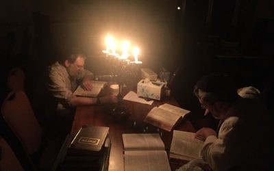 Barry Yaffe (left) and Rabbi Mendle Dickstein study Torah in the dark during the blackout at Congregation Beth Jacob at 6 a.m. March 22.