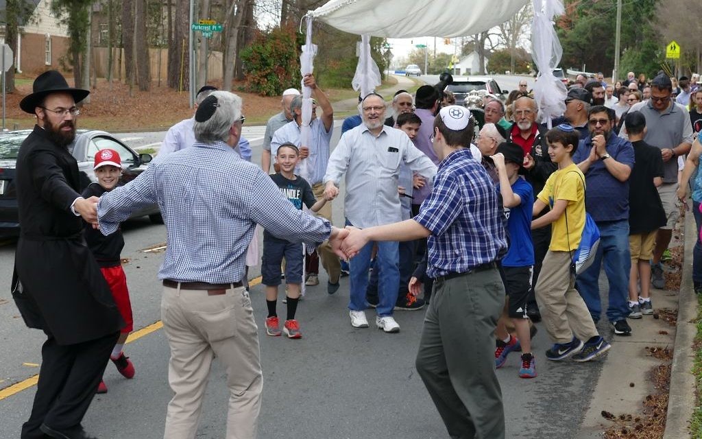 Rabbi Ephraim Silverman and Mitchell Kopelman are among those dancing in the street to celebrate the new Torah.