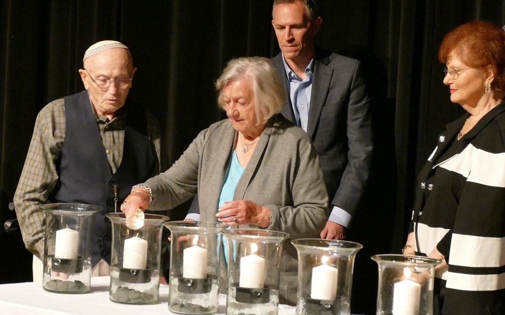 After receiving the helper candle from Marlene Besser, survivor Erica Lauten lights the fifth of six candles at the JCC ceremony with the help of Bernie Gross.