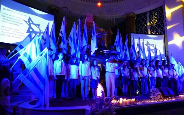 While members of the Israeli Scouts and B’nei Akiva hold Israeli flags, Epstein School student Joshua Sampson plays the violin to lead the singing of “Hatikva” at the end of the Yom HaZikaron ceremony April 30 at The Temple.