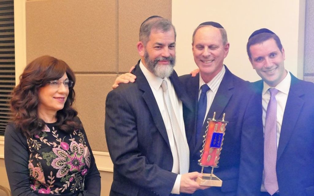 Rabbi Ilan Feldman accepts the Beth Jacob award on behalf of his wife, Miriam, from synagogue Vice President Cliff Alsberg and President Josh Joel (right).
