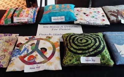 Pillows created by Peach State Stitchers for a convention challenge reflect the theme of “We Have a Dream for Peace.”