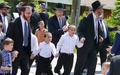 Beth Jacob members, including Rabbi Ilan Feldman, dance their way along Breezy Lane to bring the new Torah home.