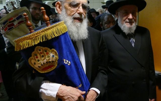 Accompanied by Rabbi Israel Meir Rau, Rabbi Emanuel Feldman carries one of Beth Jacob’s Torahs from Heritage Hall to the new sanctuary.