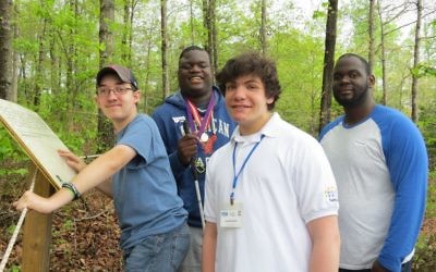 Evan Barnard helps visually impaired students make their way along the Whispering Woods Braille Trail in Buford during Global Youth Service Day.