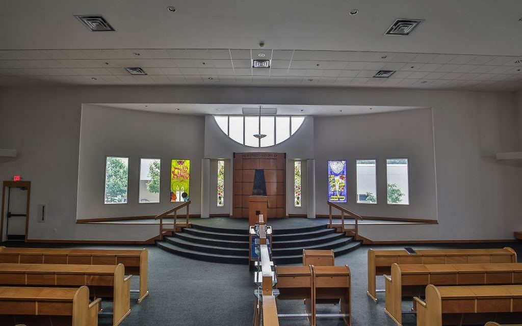 Four of the eight windows flanking the ark at Congregation Beth Tefillah now have stained-glass designs, while the other four windows await donors.