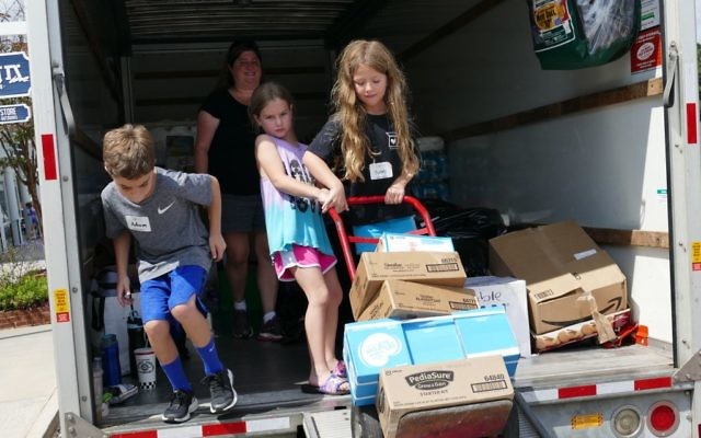 Children help load the truck that took supplies from the Packaged Good to Keller Williams’ office in East Cobb, where Walton High football players helped make the transfer to a Super Movers semi.