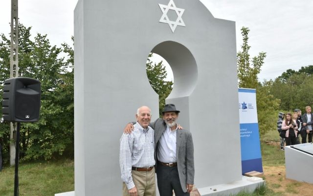Ed Goldberg of Atlanta (left) and Mark Upfal of Ann Arbor, Mich., stand in front of the memorial monument in the cemetery in Kaluszyn.